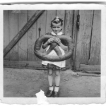 BLack and white photo of a young Lucia holding a giant pretzel
