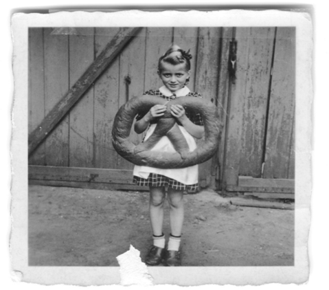 BLack and white photo of a young Lucia holding a giant pretzel